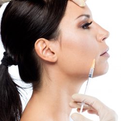 Portrait of beautiful young woman getting botox cosmetic injection in her face over white background.