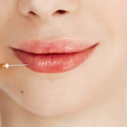 Close up photo of medical botox injection in lips over white background. Facial treatment.